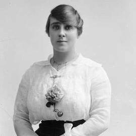 Studio portrait of a young woman wearing a large rose.