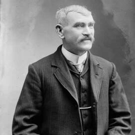 Studio portrait of a seated man.