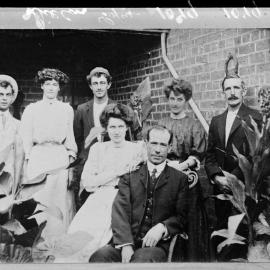 A group of unidentified men and women outside a brick building.