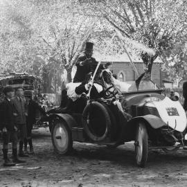 An open car carrying people in costume, possibly dressed as minstrels.