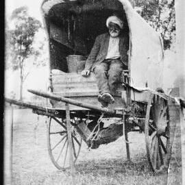 A man wearing a turban and sitting in a covered cart.