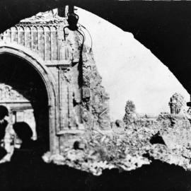Soldiers silhouetted in front of a damaged building.