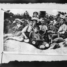 A group of eight men, some wearing items of military clothing.
