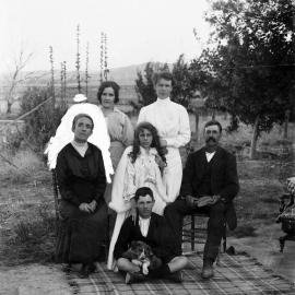 A group of six people on a rug in a rural setting.