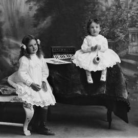 Portrait of two young girls seated in a studio.  Family name Wallace.
