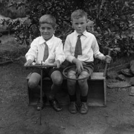 Two unidentified boys seated together on a wooden box.
