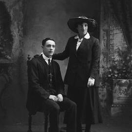 Studio portrait of a standing woman and a seated young man. Family name possibly Hodgetts.