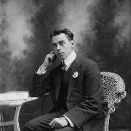 Studio portrait of a young man seated in a wicker chair.  Family name Gellispie or Gillispie.