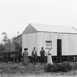 People standing in front of a primitive dwelling, possibly near the Murray River, Victoria.
