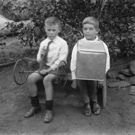 Two unidentified boys seated together on a wooden box.