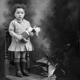Studio portrait of a young girl standing on a chair.  Family name Peterson.