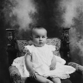 Studio portrait of a baby wearing a dress.