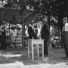 An unidentified man holding a tennis trophy.