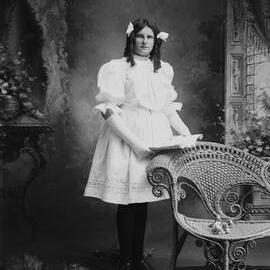 Studio portrait of a girl in a white dress and long gloves.  Family name possibly Branston.