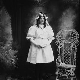 Studio portrait of a girl in a white dress and long gloves.  Family name possibly Branston.