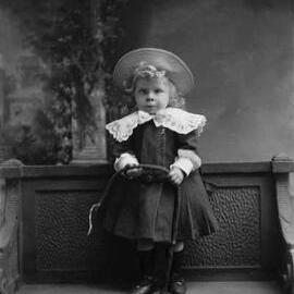 Studio portrait of a young girl holding a whip.  Family name Oake.