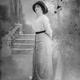Studio portrait of a woman wearing a hat and long skirt.