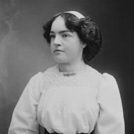 Studio portrait of a seated woman wearing a white blouse.