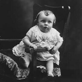 Studio portrait of a baby wearing a dress.  Family name possibly Stowell.