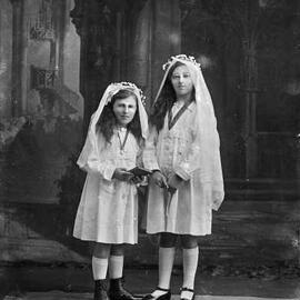 Studio portrait of two girls in white dresses and veils.  Family name Gillespie.