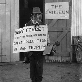 A man wearing an animial skin balaclava outside a war museum, possibly at Benalla, Victoria.
