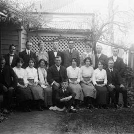Posed group of  people outside a timber residence.