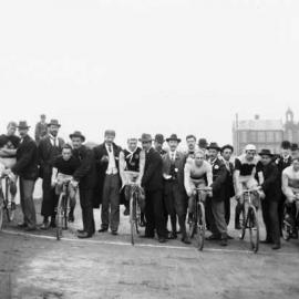 Seven cyclists with supporters and onlookers.