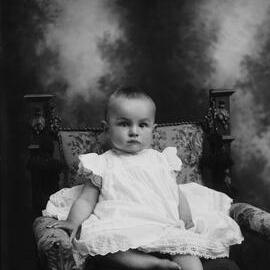 Studio portrait of a baby wearing a dress.