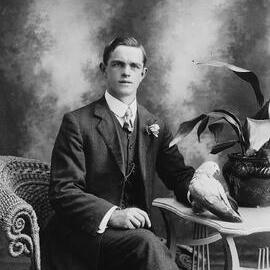 Portrait of an unidentified young man holding a parrot.