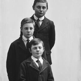 Studio portrait of three boys in identical clothing.  Family name possibly Brennan.