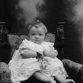 Studio portrait of a  baby wearing an elaborate dress.  Family name Gibson.