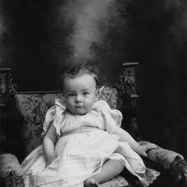 Studio portrait of a baby wearing a dress.  Family name either Arnel or Arnold.