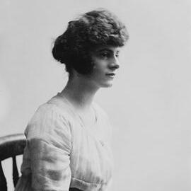 Studio portrait of a seated young woman in profile.