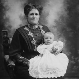 Studio portrait of a seated woman holding a baby.
