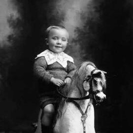 Studio portrait of a boy on a rocking horse. Family name Hopkins.