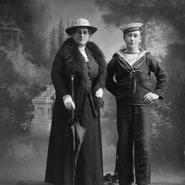 Studio portrait of a woman wearing a fur stole and a young man dressed in a naval uniform.  Family name possibly Dermondy.