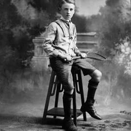 Studio portrait of a boy seated on a wooden pedestal.  Family name Allen.