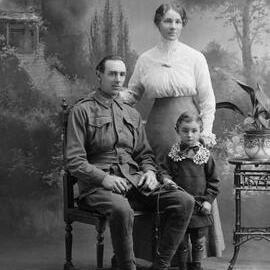 Studio group portrait of a seated man, with a women and boy standing alongside.  Family name Shimmin or Shimmer.