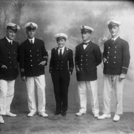 A group of men and a young woman dressed in naval officers’ uniforms or costumes.