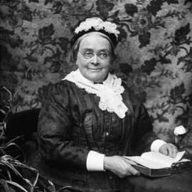 Studio portrait of a seated woman wearing a hat.