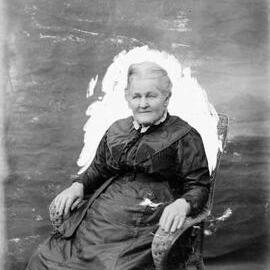 Portrait of an unidentified elderly lady seated in a wicker chair.