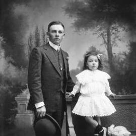Studio portrait of a young man standing with a young girl.  Family name McKenzie.