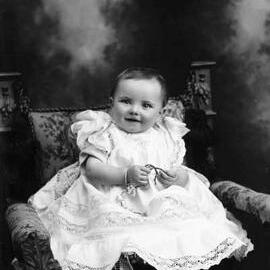 Studio portrait of a baby wearing a dress.  Family name Carroll.