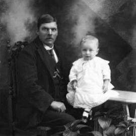 Studio portrait of a seated man with a baby.  Family name Allison or Allisen.