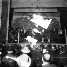 A boxing match on the stage of a hall with an audience in attendance.