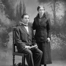 Studio portrait of a woman with a young man holding a testamur.  Family name Moore.