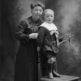 Studio portrait of a woman with a young boy who holds a bugle.