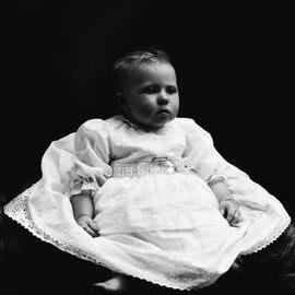 Studio portrait of a baby wearing a dress.  Family name Hunt.