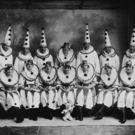 A posed group of men and women dressed in clown costumes.