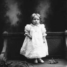 Studio full-length portrait of a young girl standing on a bench.